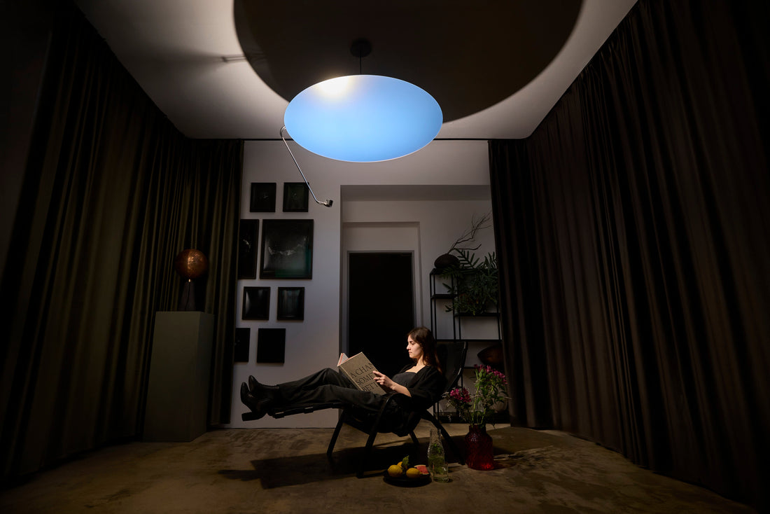 A woman reading in a reclining chair under Sunday Light in a dark, curtained room