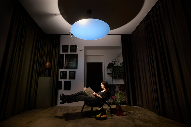 A woman reading in a reclining chair under Sunday Light in a dark, curtained room