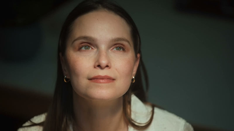 A woman looking up into the light, her face lit softly from above
