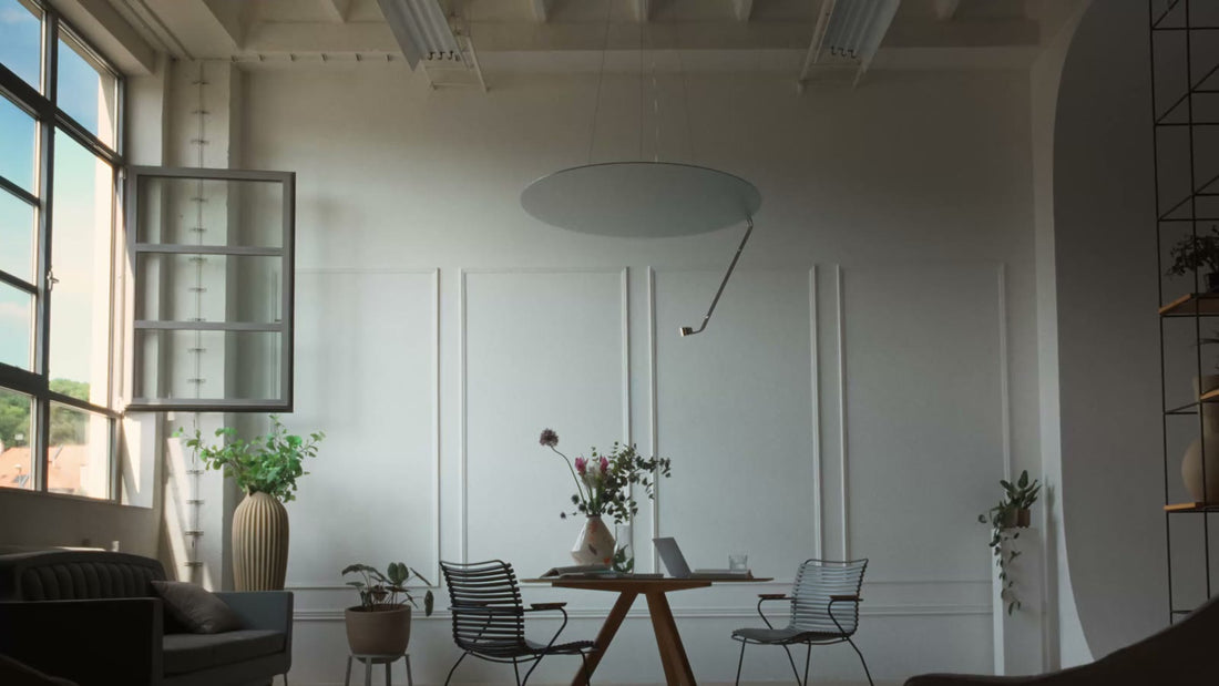 Sunday Light hanging over a wooden table in a tall white room with large windows