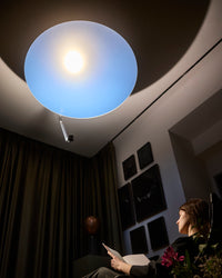 Woman reading under the warm evening glow of Sunday Light indoor sunlight lamp